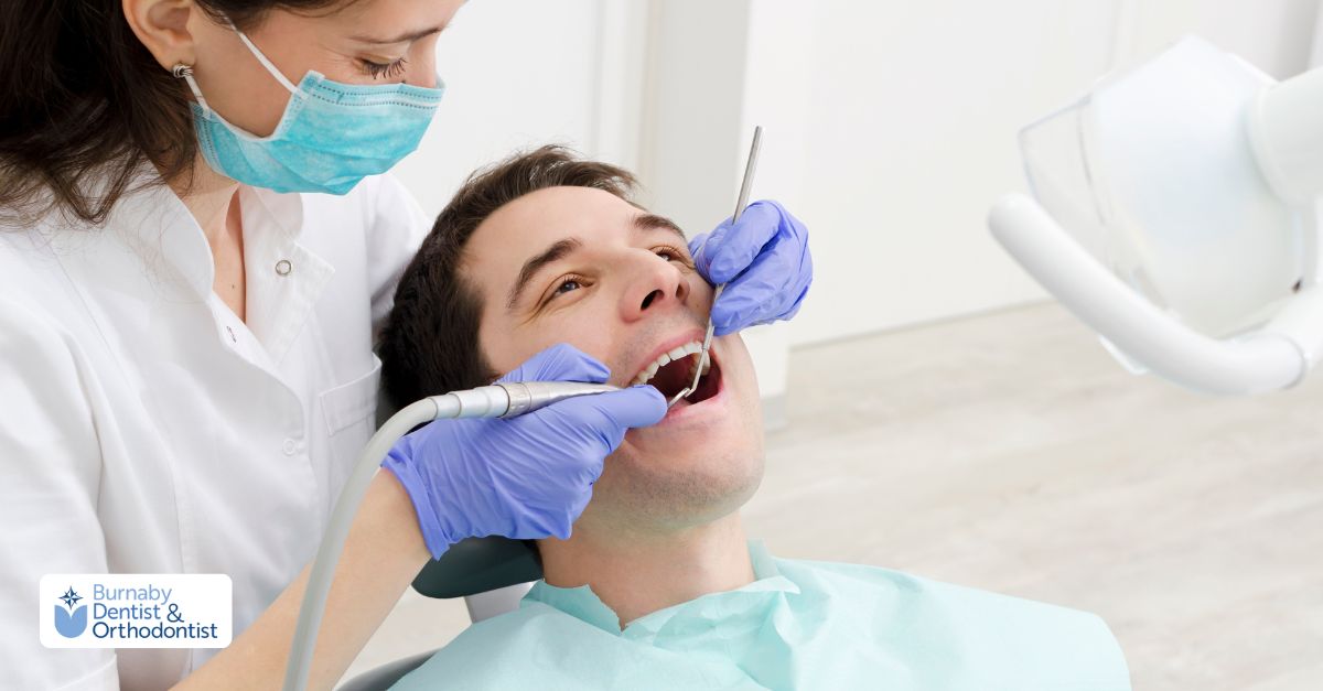 A man in a dental chair smiles during his dental exam and cleaning appointment.