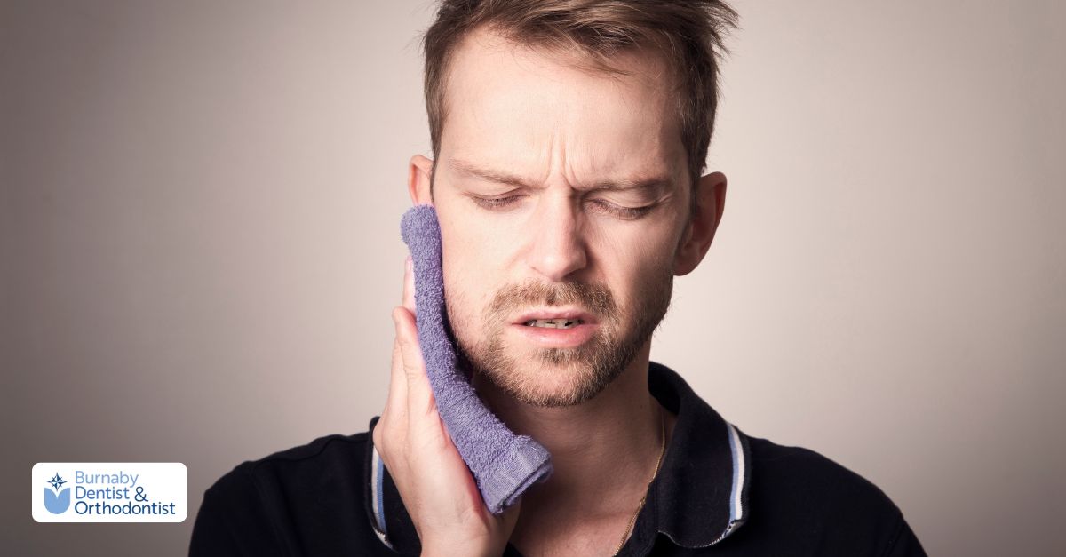 A man holds his finger to his mouth, indicating pain during tooth extraction recovery.