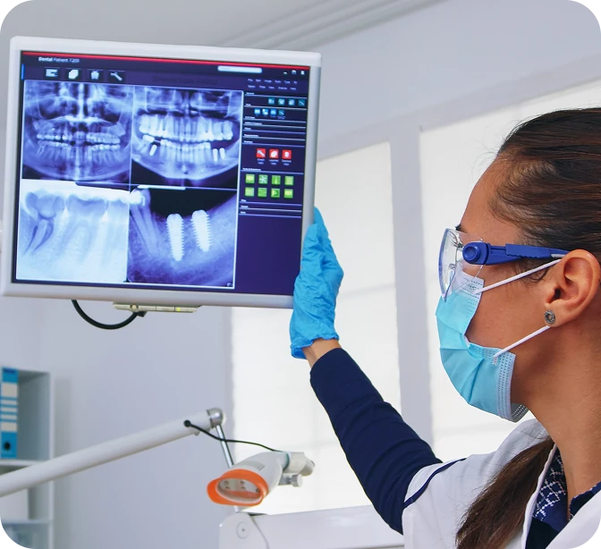 Dentist and patient reviewing dental X-ray on a monitor.