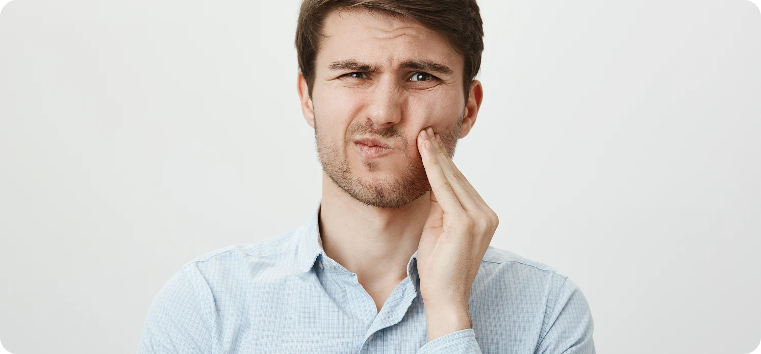 Young man holding his jaw in pain from a dental problem