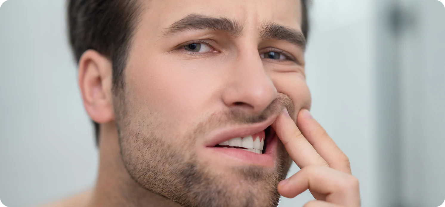 Man touching his cheek with a painful expression, indicating toothache.