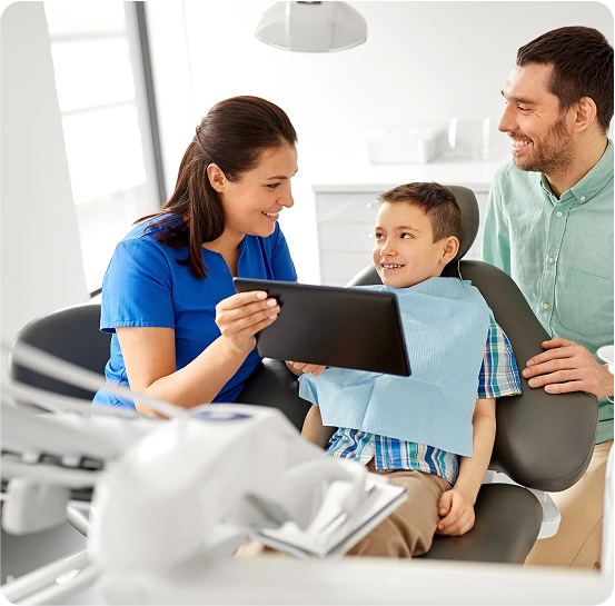 Dentist showing a young boy and his father dental X-rays on a tablet during a consultation.