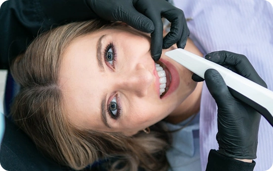 Smiling woman comparing her teeth color with a shade guide at the dentist.