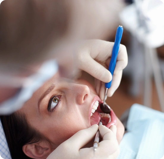 Dentist performing a dental procedure on a female patient using dental instruments.
