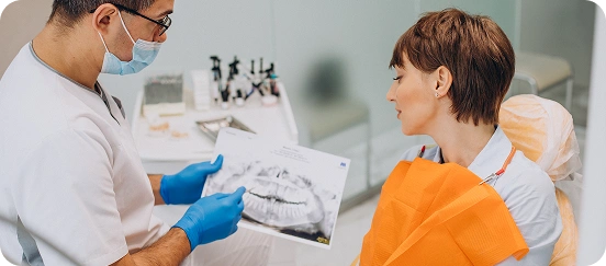 Dentist showing a dental X-ray to a female patient during a consultation at the clinic.