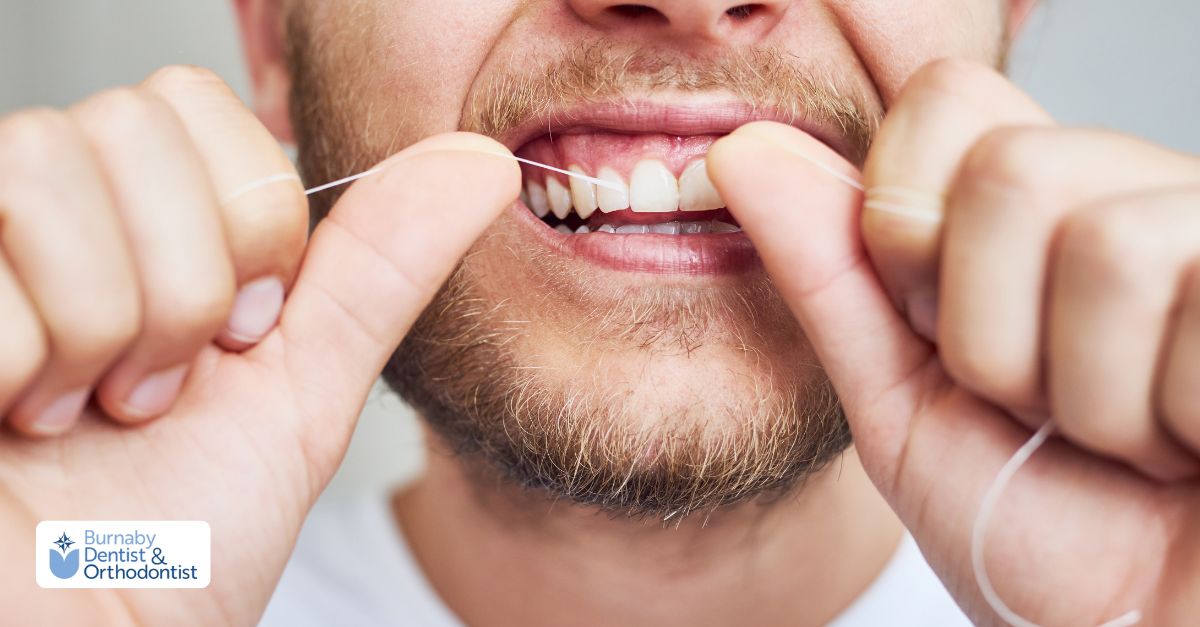 Person cleaning between teeth with dental floss, showing oral care with spacers.