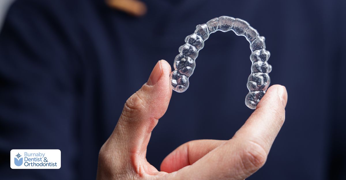 Invisalign clear aligner held between fingers, showing discreet teeth straightening option