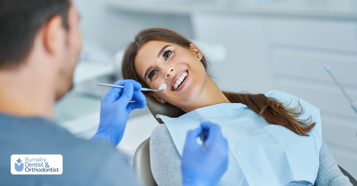 A woman is seated in a dental chair while a cosmetic dentist cleans her teeth.