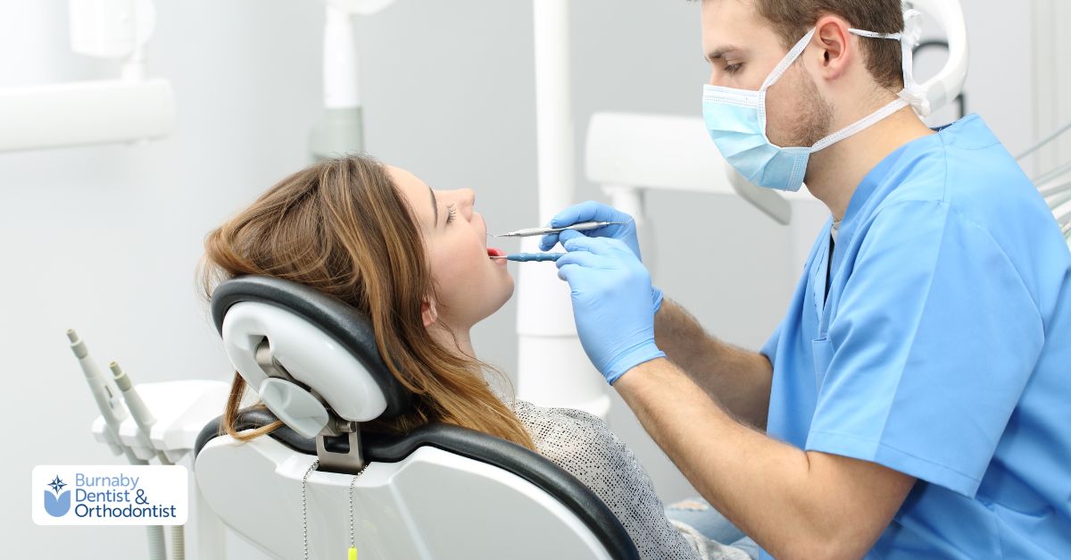 A dentist examines a woman's teeth while she sits in a dentist's chair at a family dental clinic.