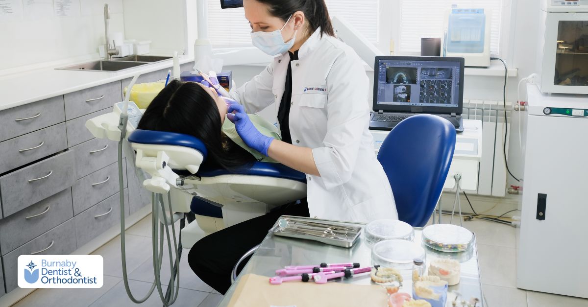  A dentist completes paperwork as two masked patients inquire about veneers and dental insurance options.