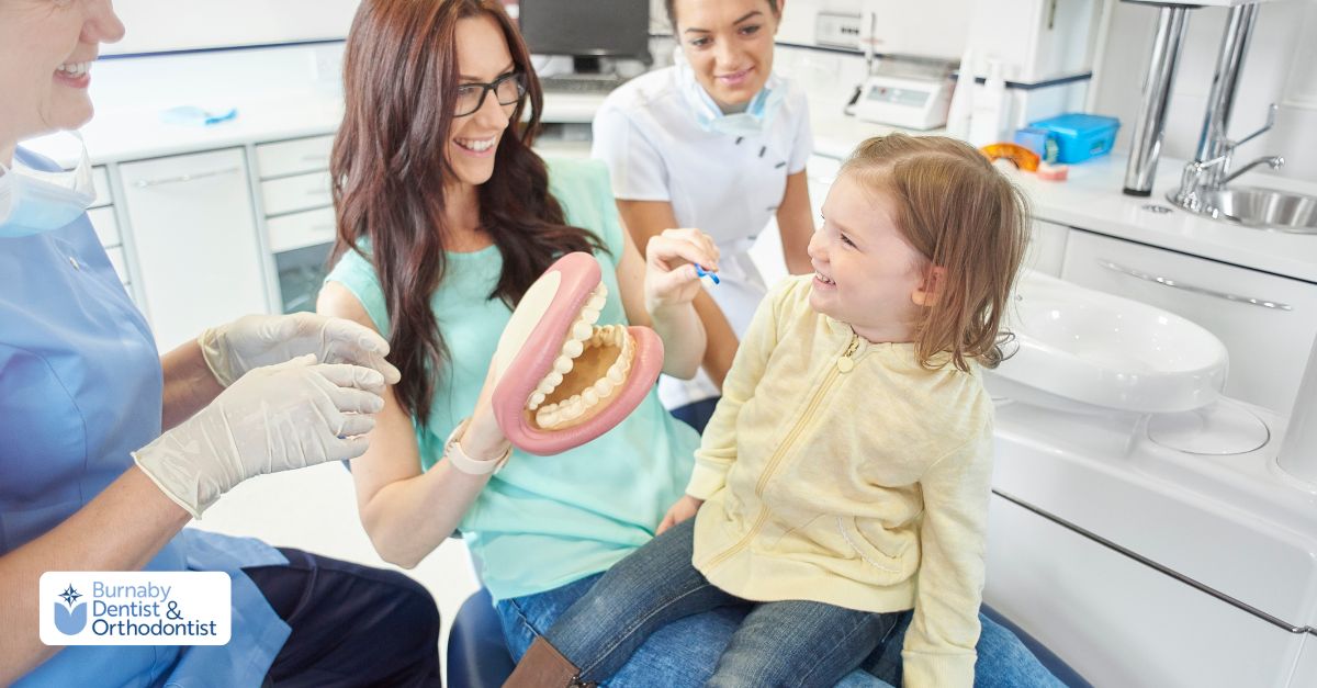  woman sits in a dental chair with a child, both smiling, highlighting the importance of family dental care.